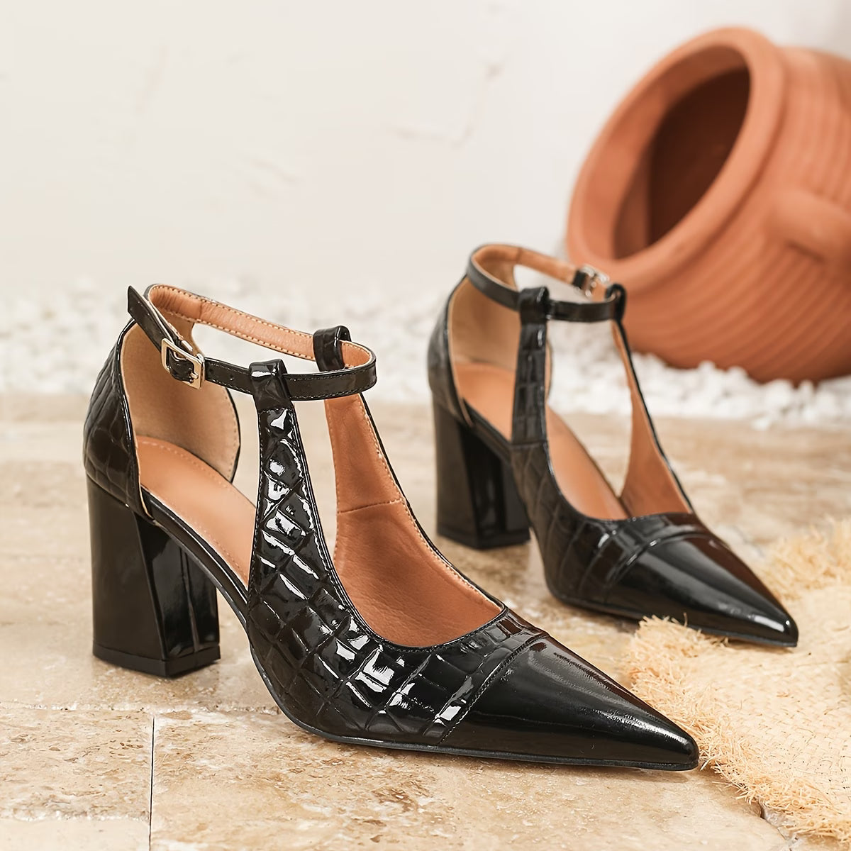 Black patent leather high-heeled shoes with a textured surface on a neutral background.
