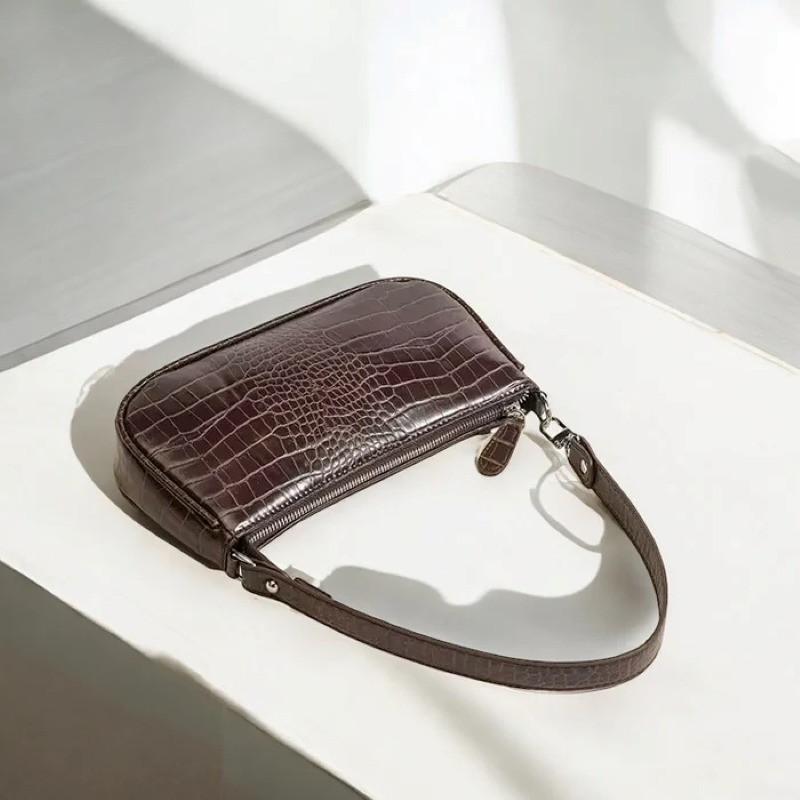Brown crocodile-patterned leather pouch on a white surface