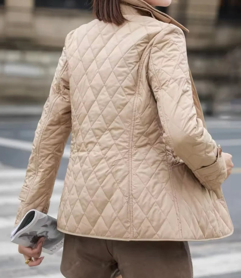 Person wearing a beige quilted jacket on a city street.