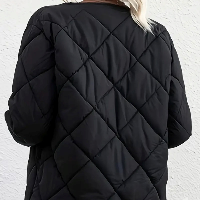 Black quilted coat worn by a person against a white background