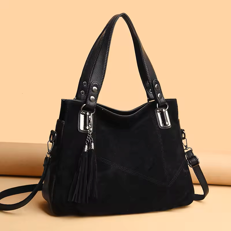 Black handbag with silver hardware on a beige background