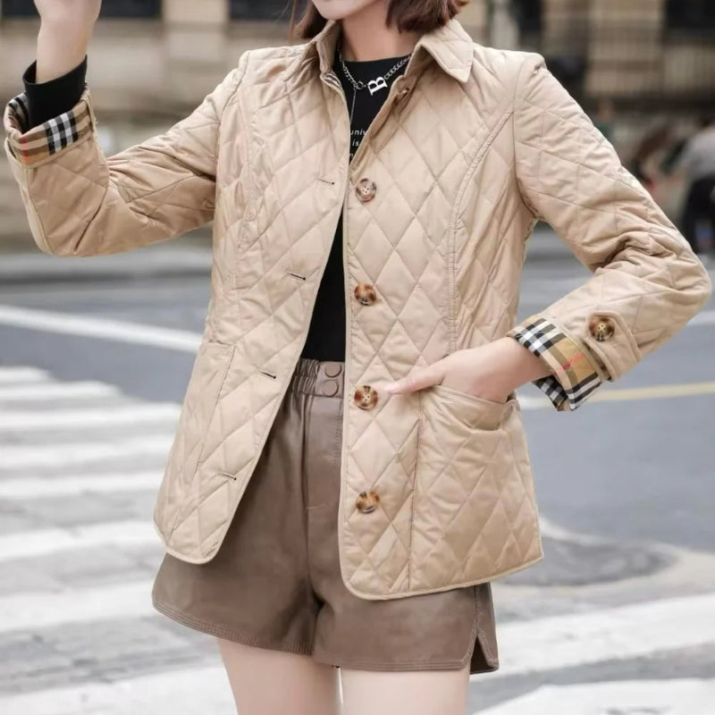 Person wearing a beige quilted jacket with a blurred urban background