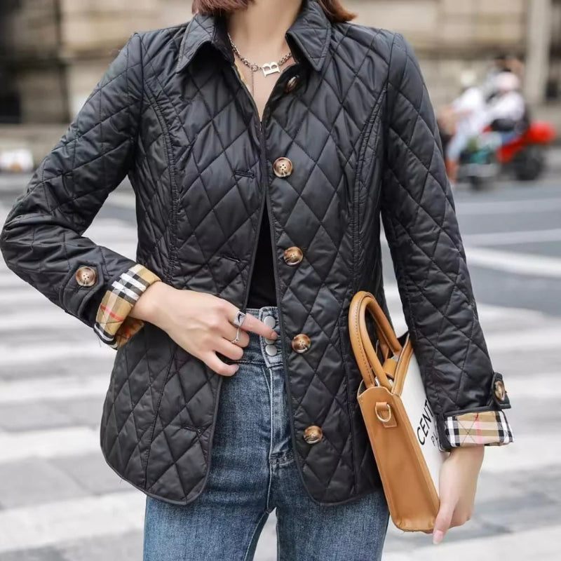 Person wearing a black quilted jacket with a blurred city street background
