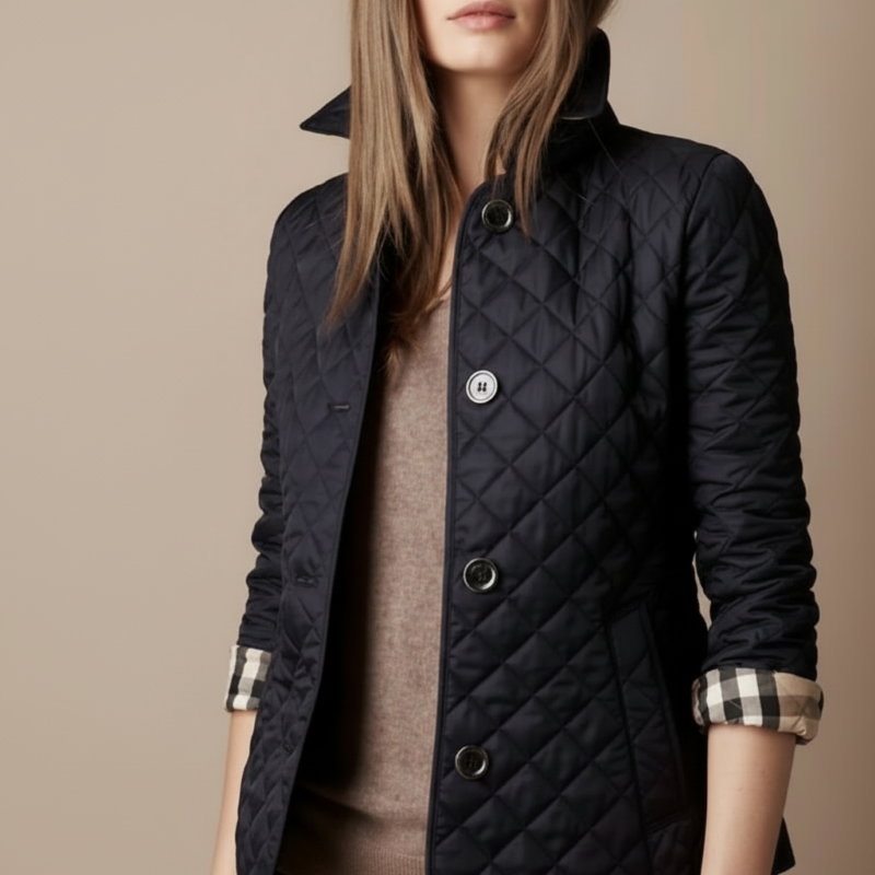 Person wearing a black quilted coat with a beige background
